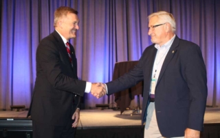 Bob Kran receiving shaking hands with Jim Mattheson